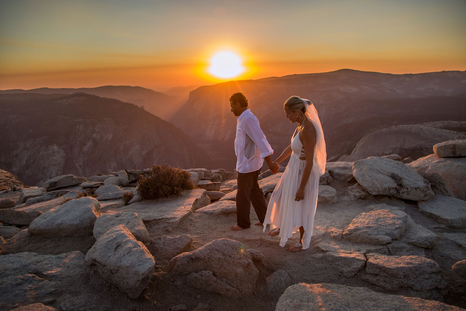 Wedding couple holding hands on Half Dome in Yosemite.