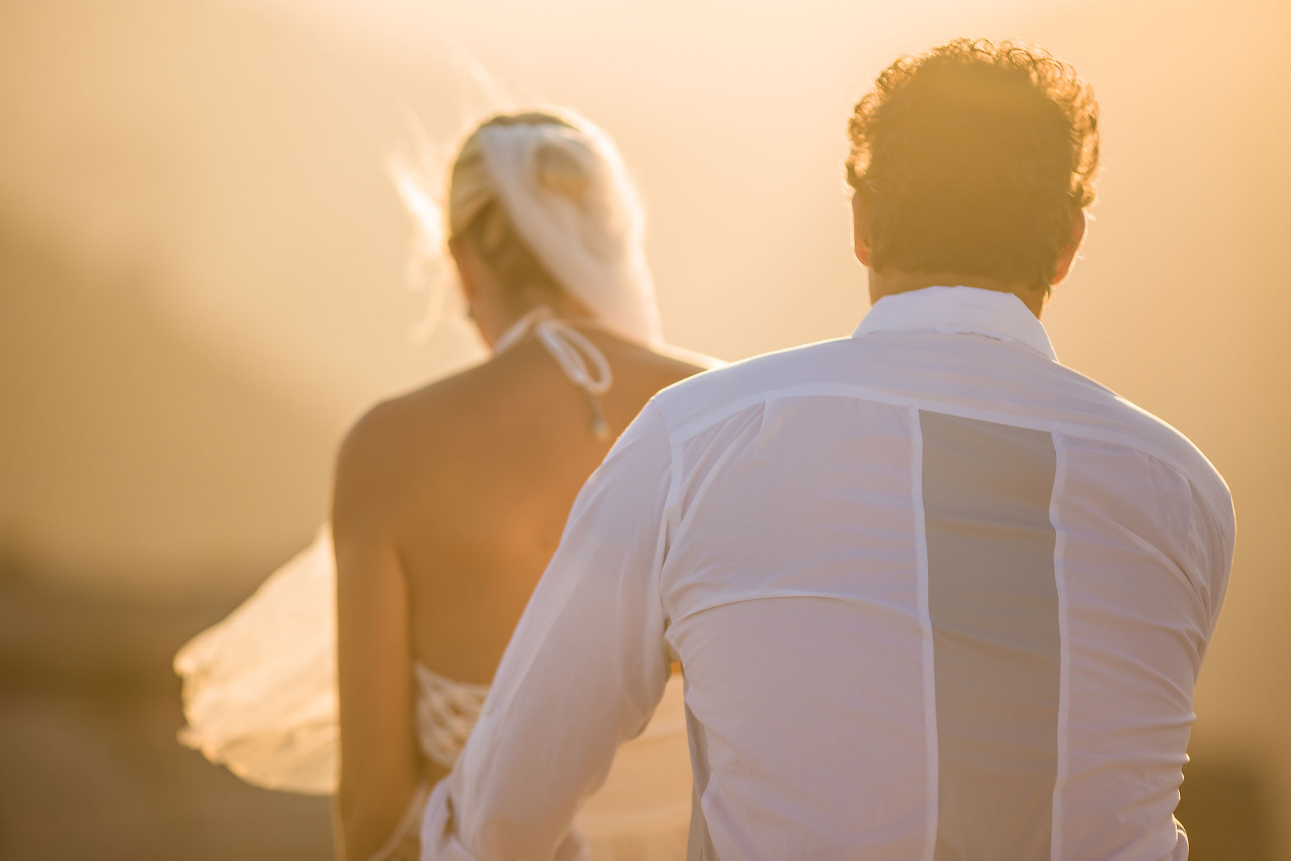 Wedding couple walking hand in hand at sunset.
